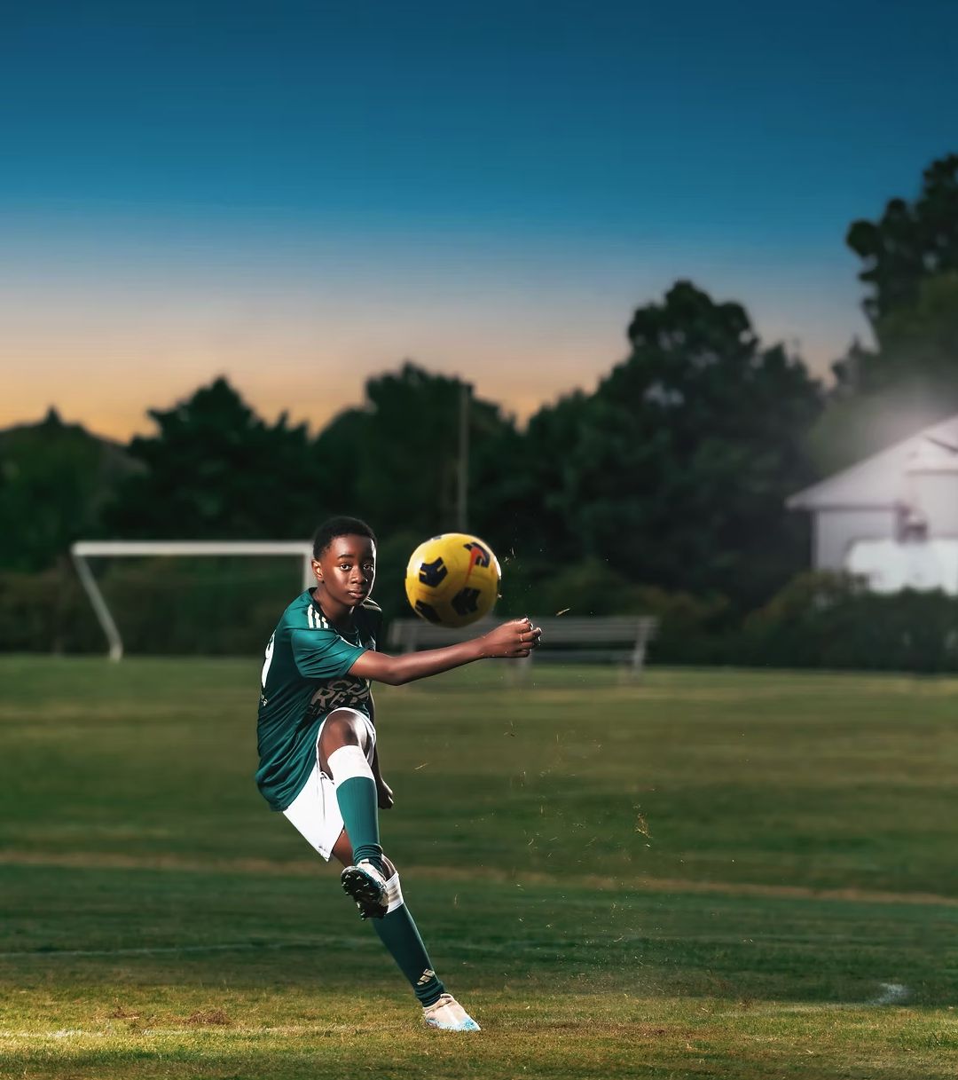 Youth soccer player striking the ball at dusk