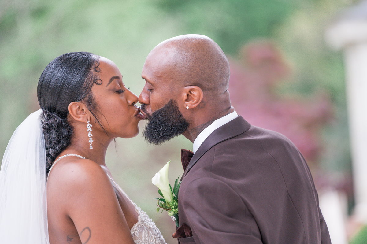 Anjanette and Ritchie kissing in a garden, soft green light