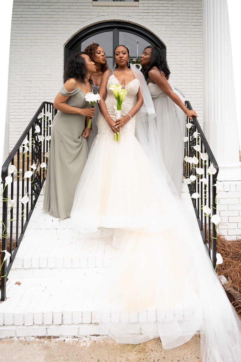 Anjanette flanked by bridesmaids in sage on the stairs