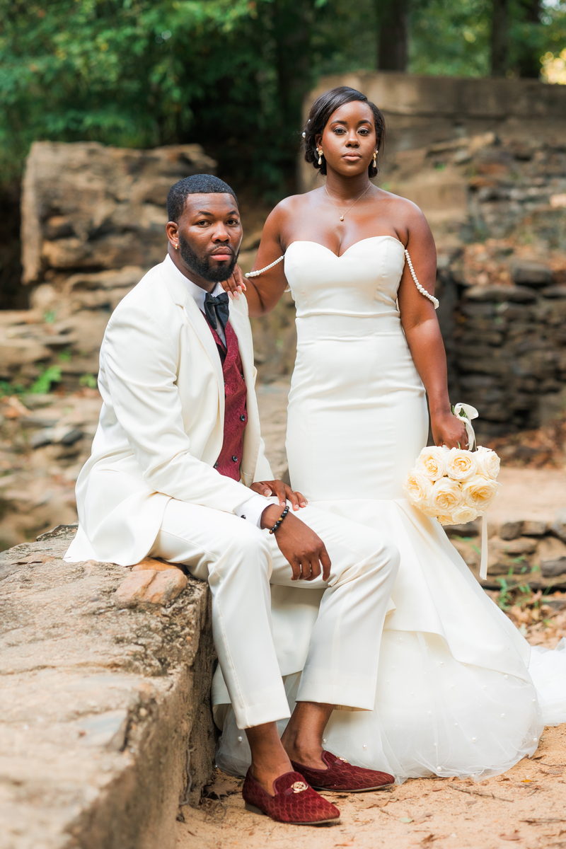 Christina and Darius seated on a stone wall by the falls