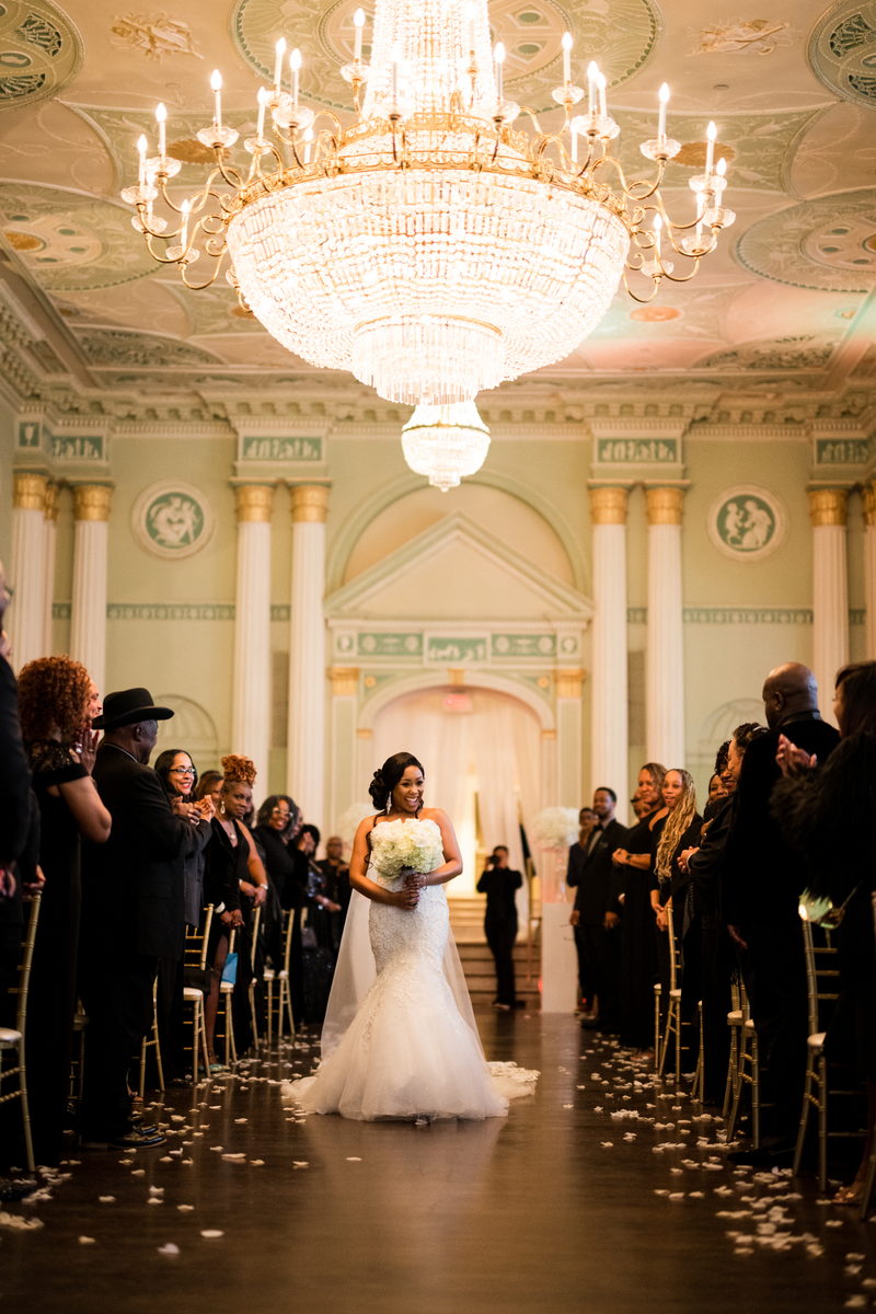 Haley walking the aisle beneath the chandelier