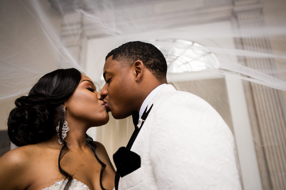 Haley and Kordel kissing beneath the veil in window light