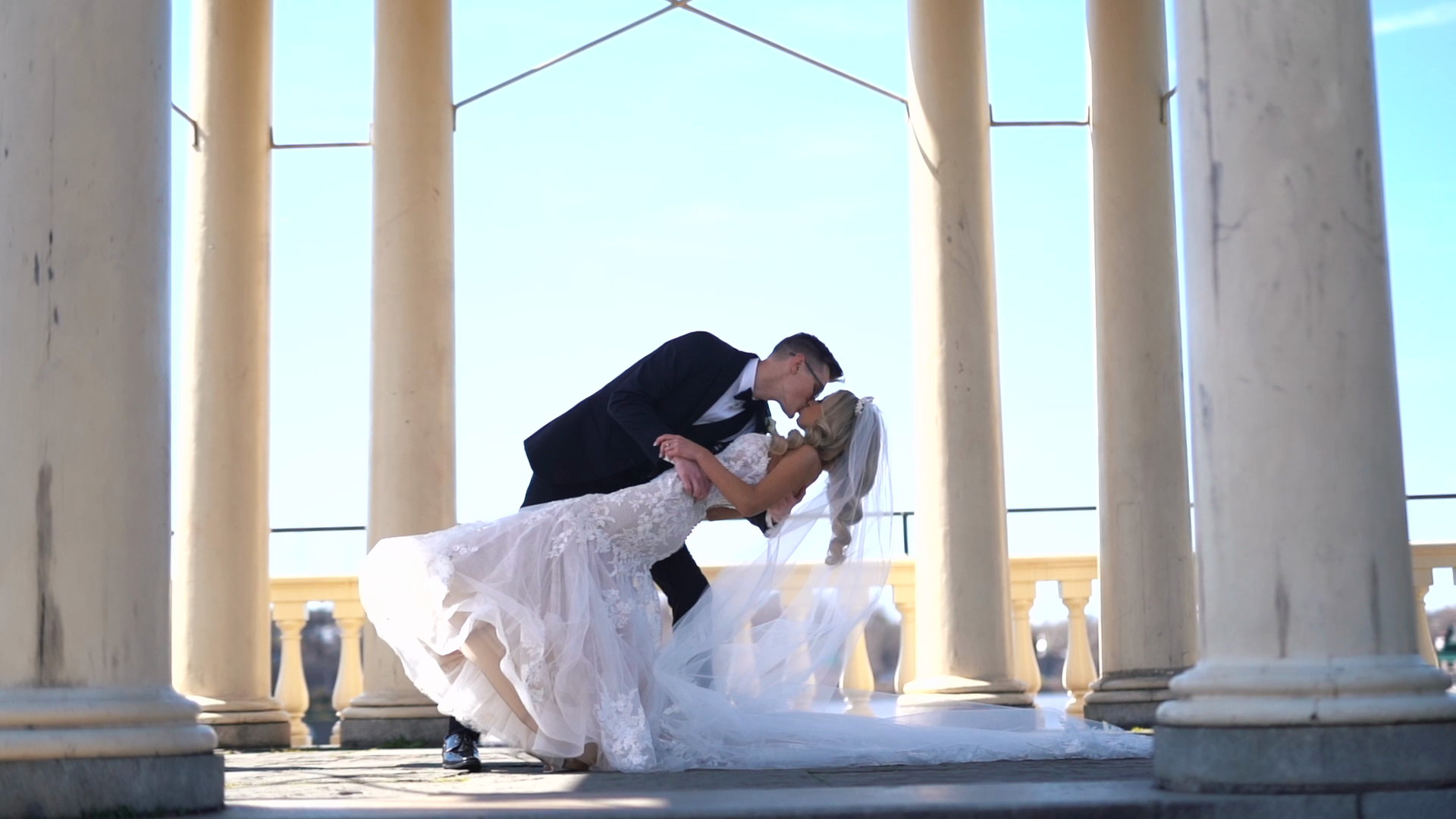 Lucus dipping Laura for a kiss between white columns