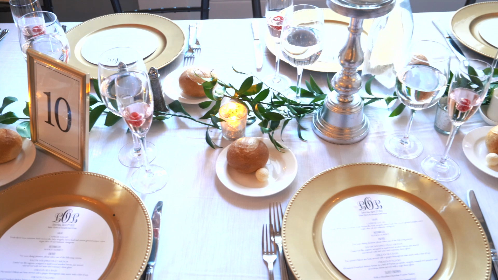 Reception table with gold chargers and greenery